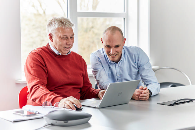 To mennesker sidder ved computer og arbejder på et projekt